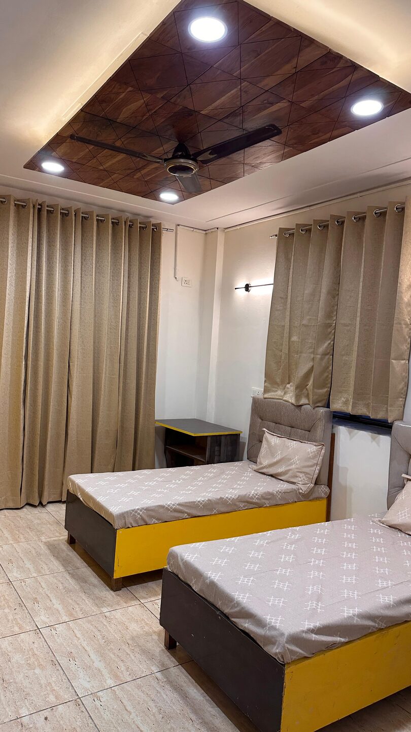 Twin-sharing room with two single beds, study desk and wooden false ceiling