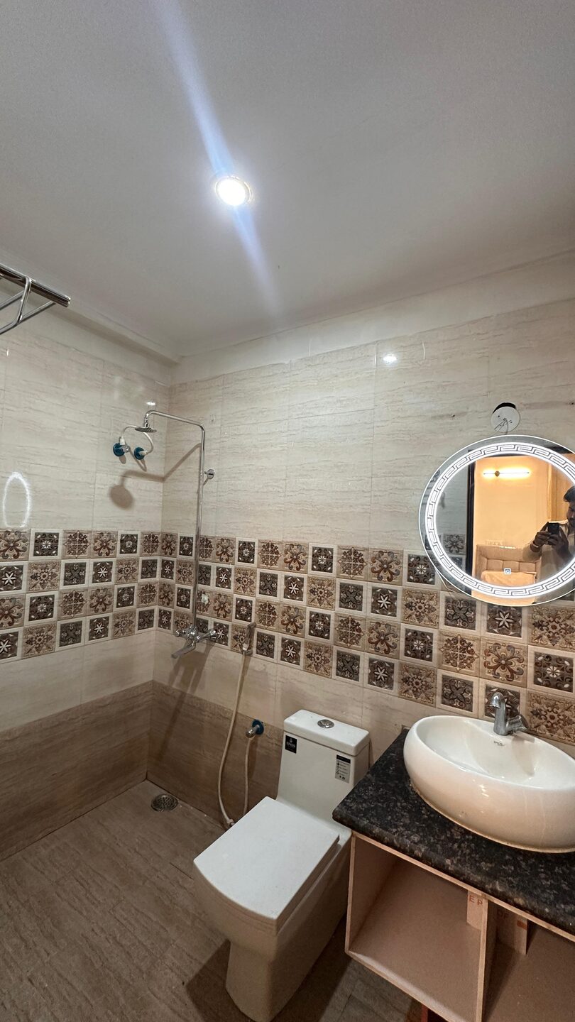 Clean attached washroom with shower, wash basin, vanity and mirror